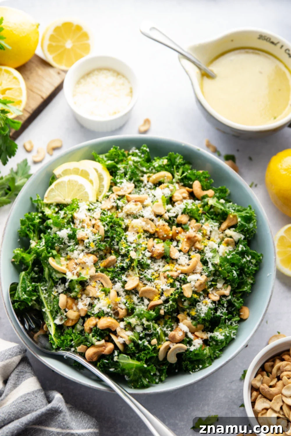 Lemon Kissed Asiago Cashew Kale 2 A vibrant and fresh Asiago Lemon Cashew Kale Salad, featuring tender massaged kale, crunchy cashews, and a generous sprinkle of asiago cheese, all glistening with a zesty lemon tahini dressing.