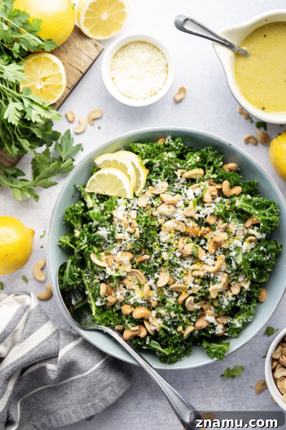 Lemon Kissed Asiago Cashew Kale 5 Ingredients for the lemon tahini dressing, including fresh lemons, honey, Dijon mustard, tahini, and olive oil, laid out on a kitchen counter.