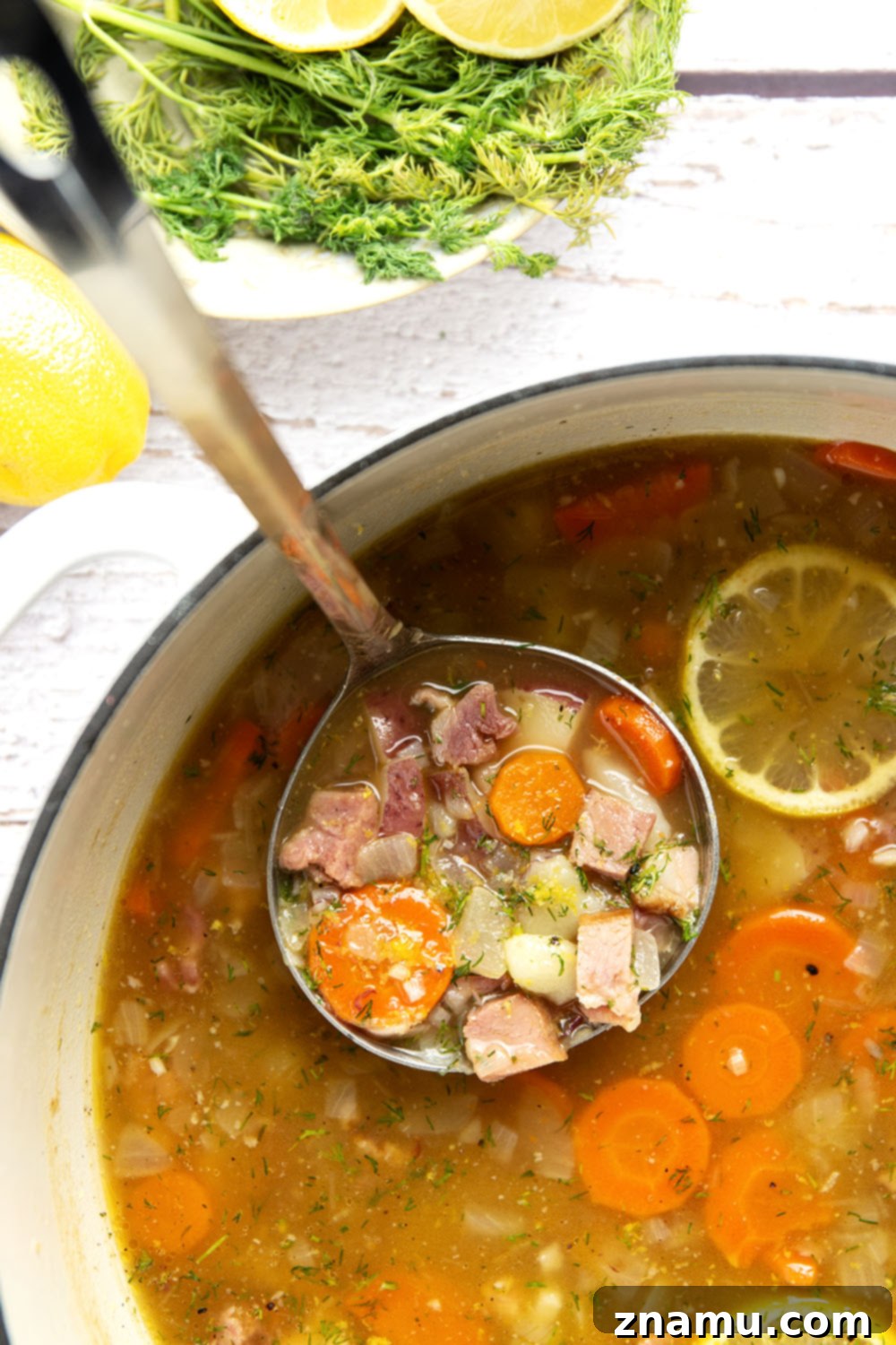 Bright Lemon Dill Ham Potato Soup 6 A ladle serving creamy Lemon Dill Ham Potato Soup into a bowl, garnished with fresh dill.