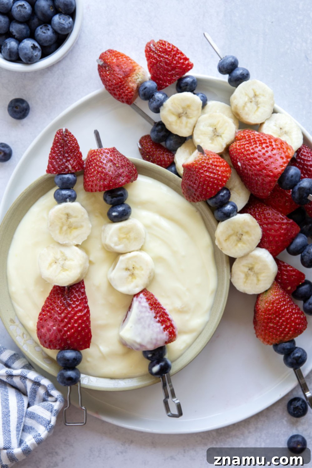 Patriotic Fruit Skewers with Creamy Vanilla Dip 6 Platter of Red White and Blue Fruit Kabobs with a bowl of Vanilla Pudding Dip, ready to serve.