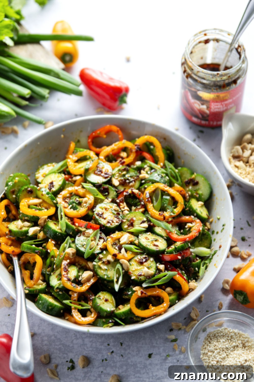 Vibrant Peanut Chili Crisp Cucumber Salad 4 Overhead shot of the fresh ingredients for Chili Crisp Peanut Cucumber Salad, including sliced cucumbers, peppers, green onions, cilantro, and chili crisp dressing.
