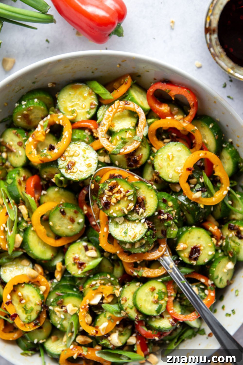 Vibrant Peanut Chili Crisp Cucumber Salad 6 A large serving bowl filled with Chili Crisp Peanut Cucumber Salad, ready to be enjoyed, with a spoon for serving.