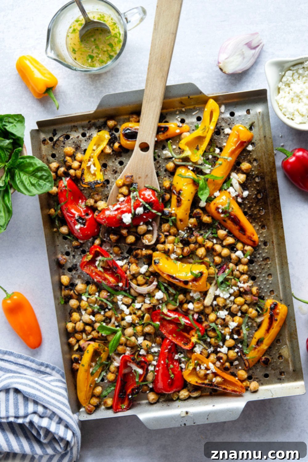 Zesty Grilled Chickpea and Sweet Pepper Medley 2 Crispy grilled marinated chickpeas and sweet peppers served in a bowl, garnished with fresh herbs and feta cheese.