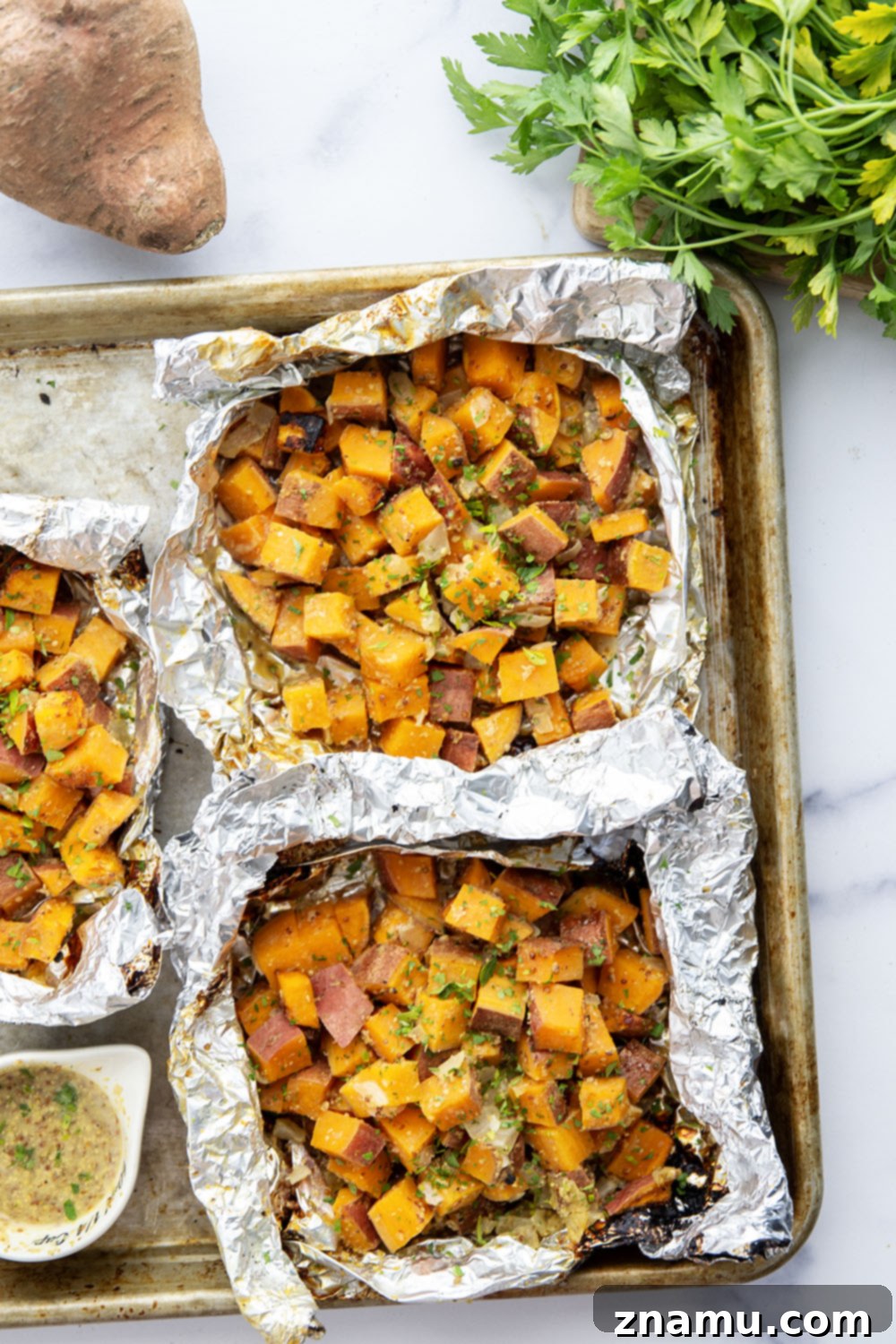 A foil packet of grilled sweet potatoes in honey mustard, ready to be served.