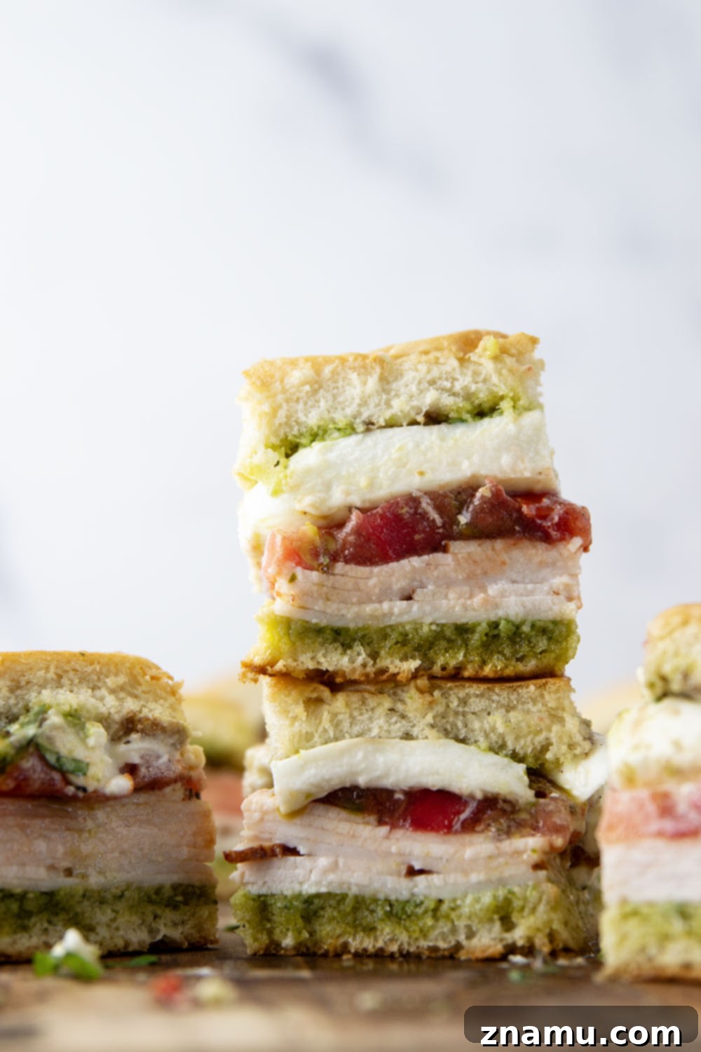 Fresh Pesto Turkey Caprese Sliders 5 Individual Pesto Turkey Caprese Sliders on a serving board, showing their inviting layers.