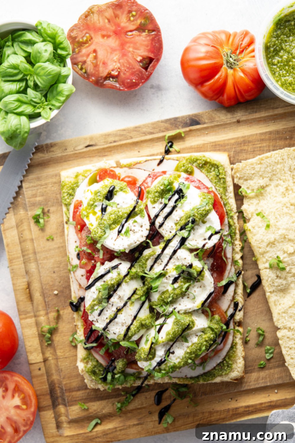 Fresh Pesto Turkey Caprese Sliders 6 A hand reaching for a Pesto Turkey Caprese Slider on a rustic wooden board.