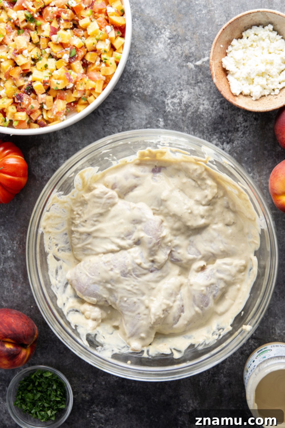 Close-up of perfectly grilled tahini chicken, garnished with peach feta salsa and fresh parsley