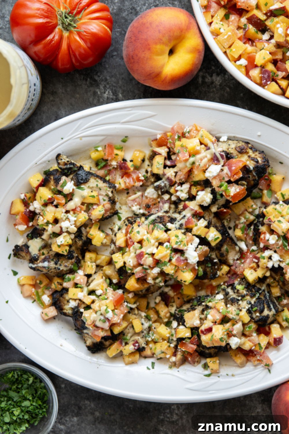 Freshly prepared peach feta salsa in a bowl, with blurred grilled chicken in the background