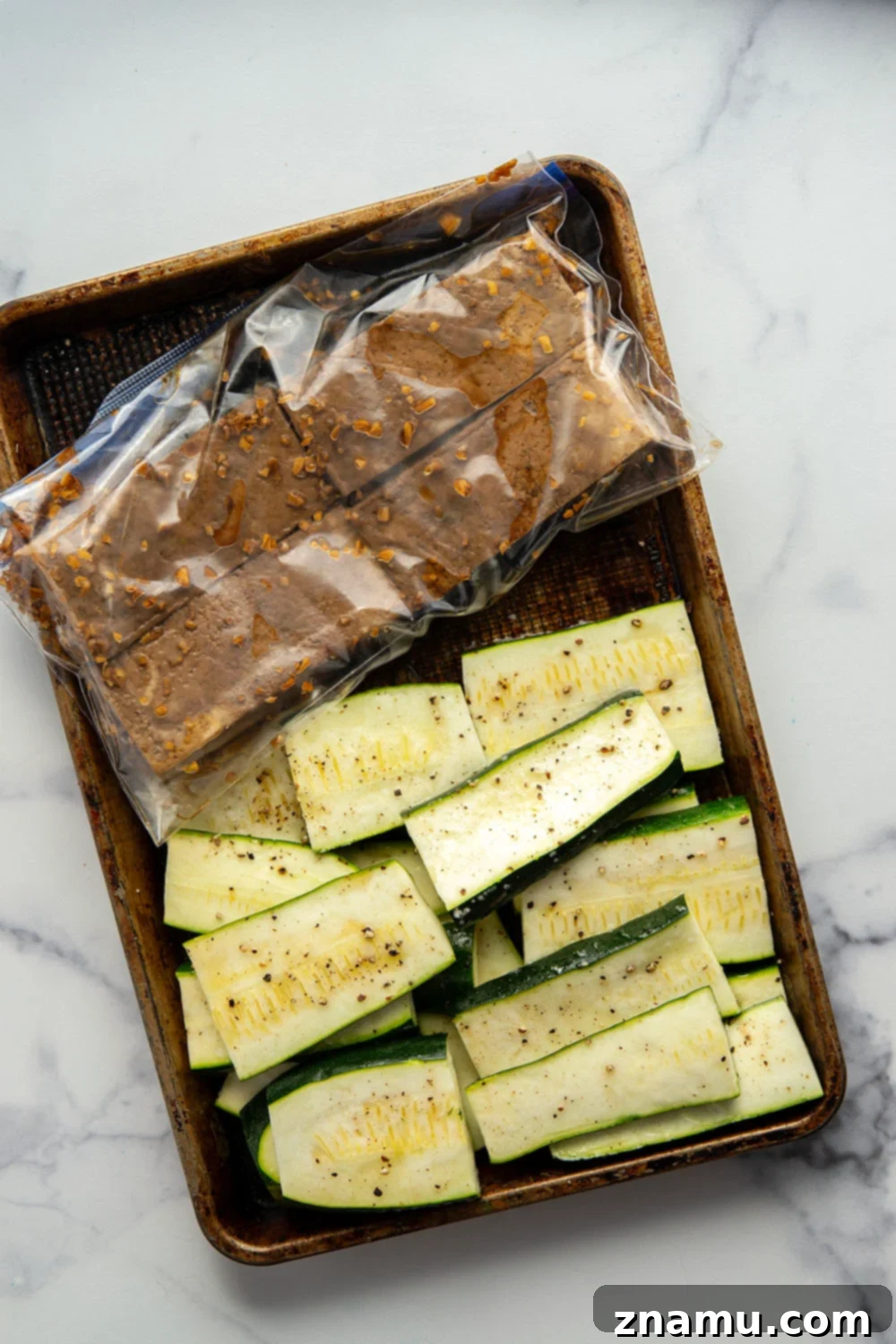 Close-up of golden-brown grilled tofu with char marks, marinated in a rich soy sauce, next to zucchini slices.