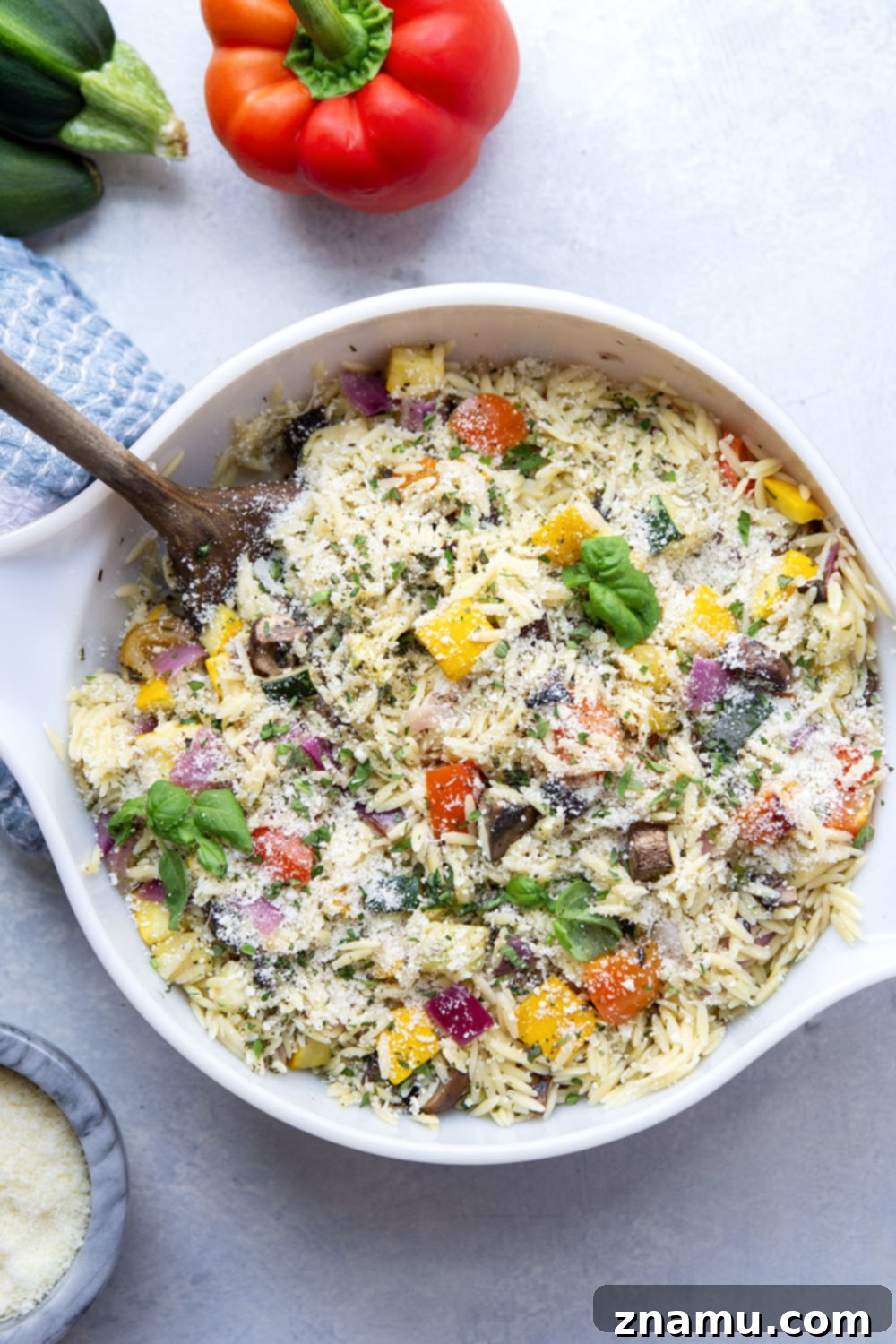 Charred Veggie Orzo Salad 4 A hand tossing grilled vegetables, orzo, and dressing in a large mixing bowl.