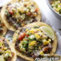 Creamy smashed black beans and a smoky grilled corn avocado salsa are piled onto these massively flavorful black bean tostadas for an easy vegetarian or vegan meal.