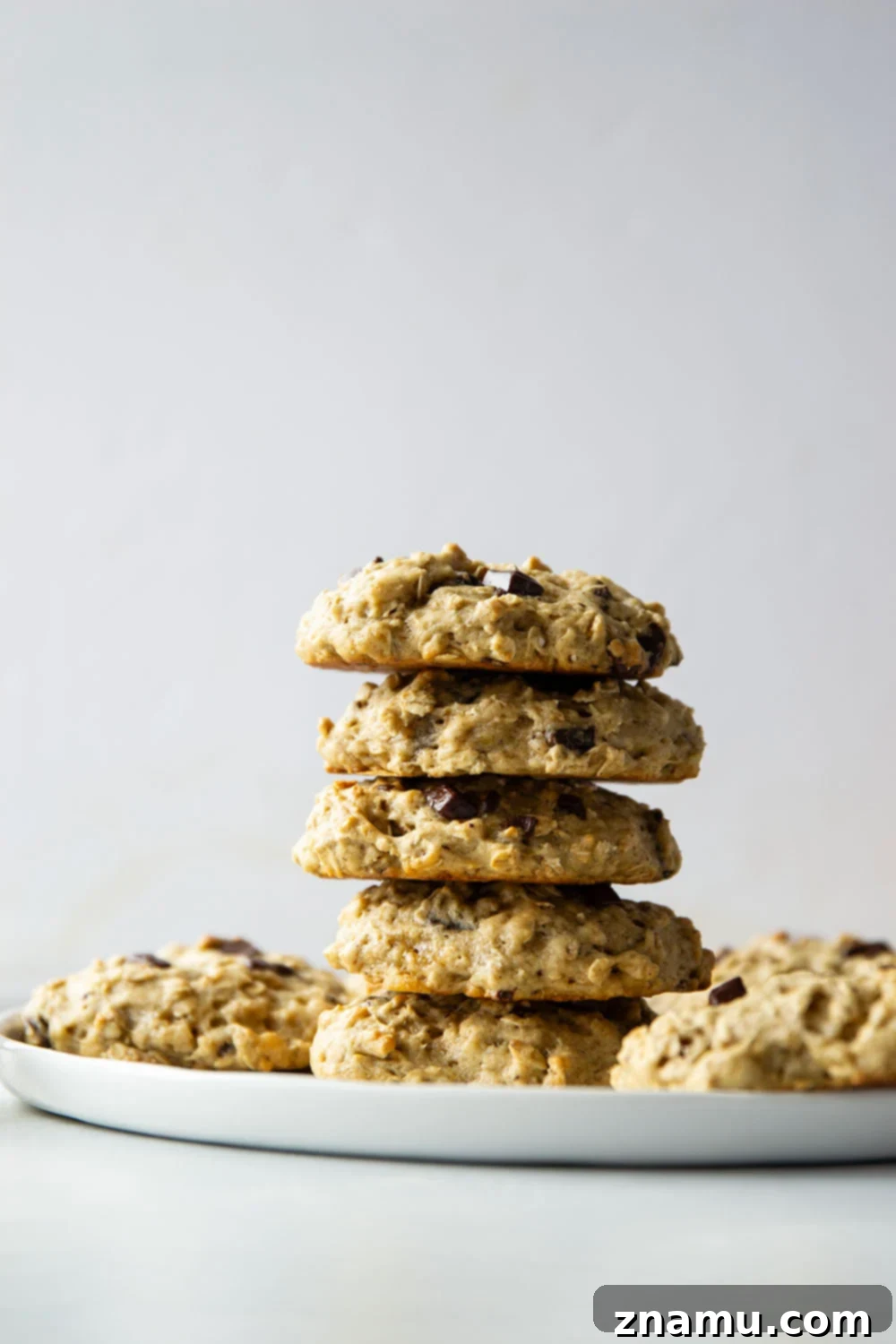 A stack of freshly baked banana oatmeal breakfast cookies, showing off their soft interior and visible oats and chocolate.