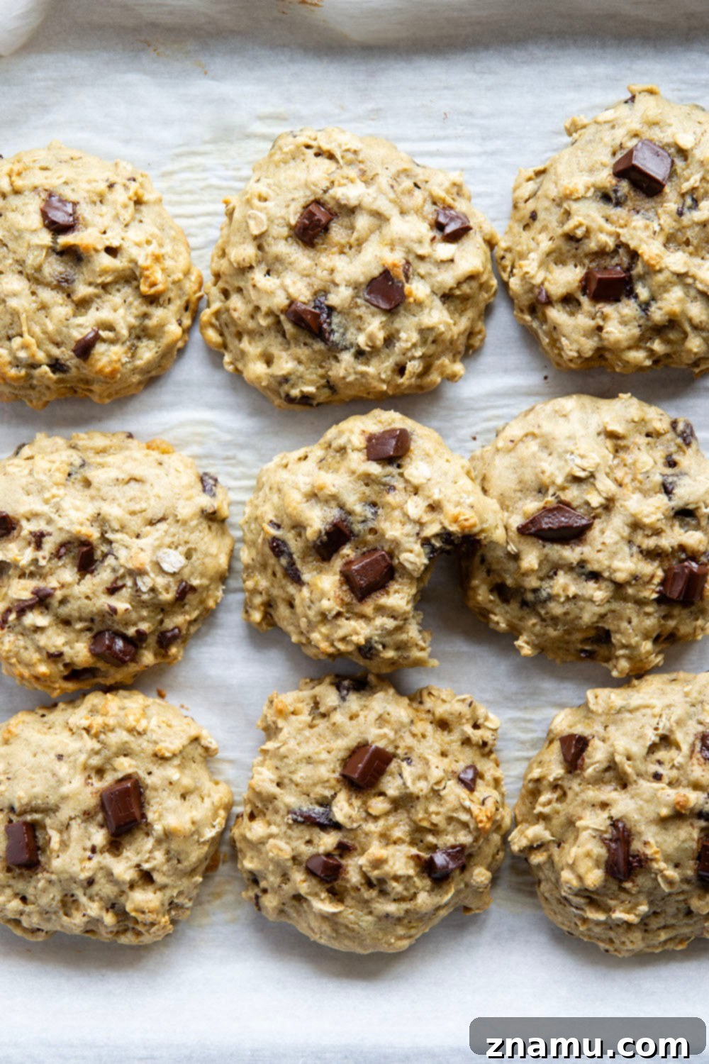 Ingredients for banana oatmeal breakfast cookies laid out on a kitchen counter: ripe bananas, oats, chocolate, flour, and spices.