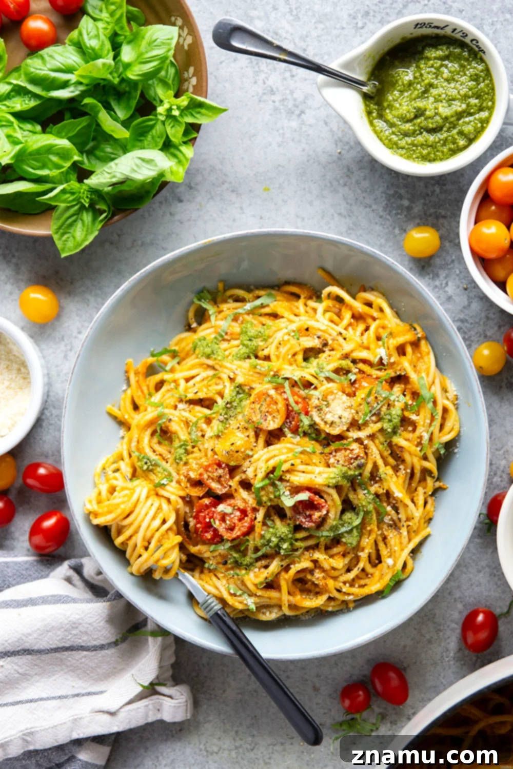 Roasted Cherry Tomato Pesto Pasta 2 A close-up shot of a plate of Pesto Roasted Cherry Tomato Pasta, showcasing the vibrant red sauce, green basil, and golden Parmesan cheese. The pasta is perfectly coated in the rich, smooth sauce.