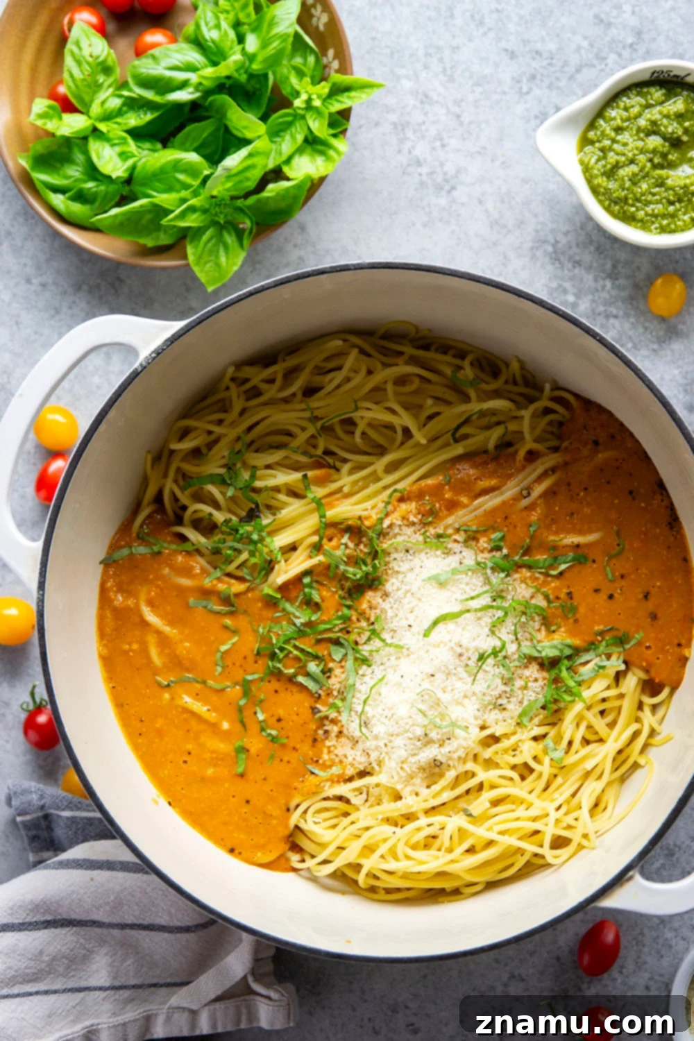 Roasted Cherry Tomato Pesto Pasta 4 A bowl of fresh basil leaves next to a small container of vibrant green pesto, highlighting key ingredients for the pasta sauce.