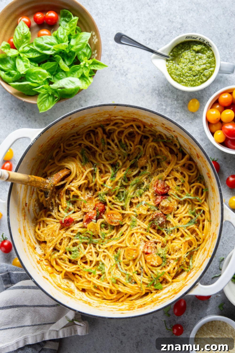 Roasted Cherry Tomato Pesto Pasta 6 A serving of Pesto Roasted Cherry Tomato Pasta topped with fresh basil and grated Parmesan cheese, ready to be enjoyed. A fork is resting on the side of the bowl.