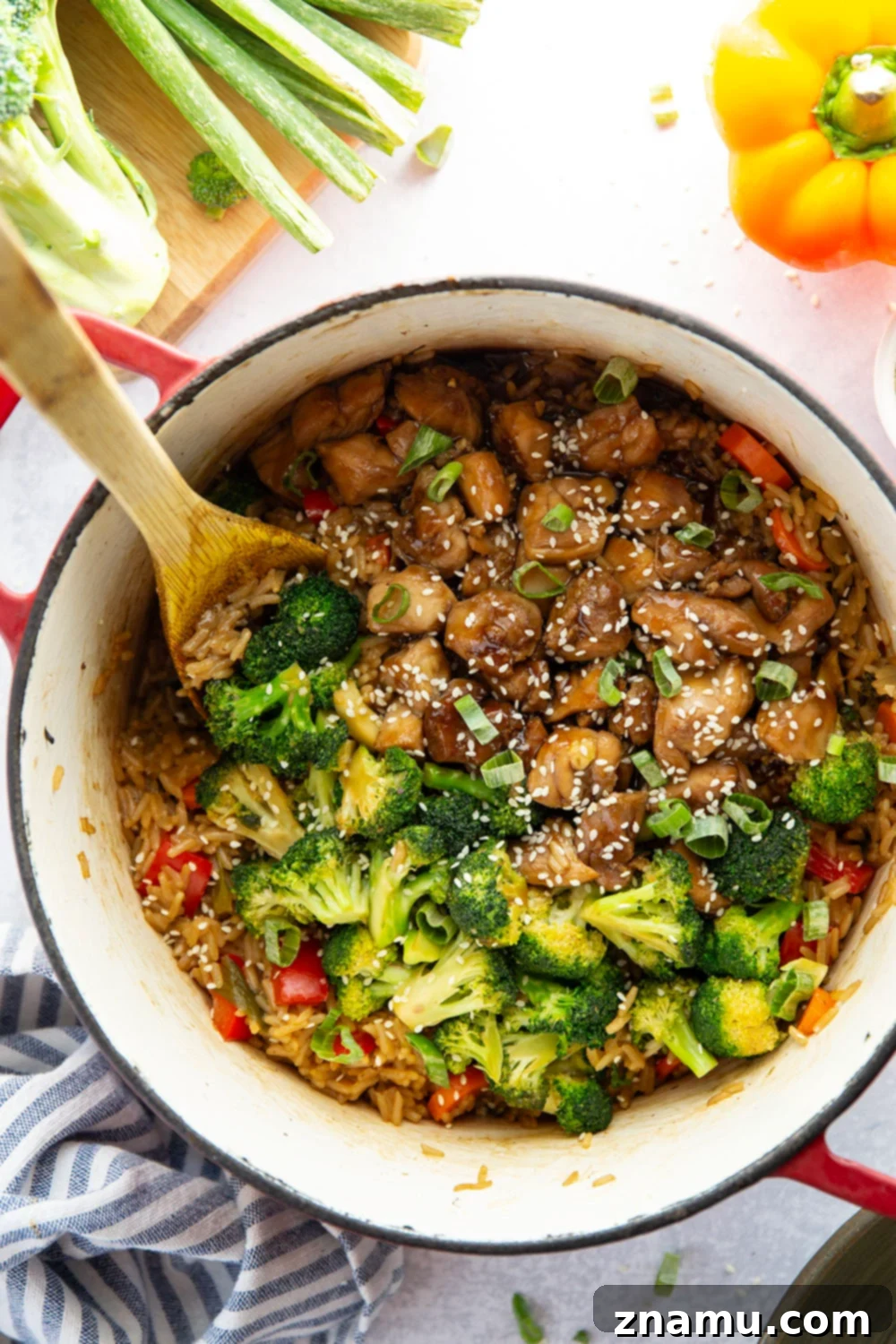 Ingredients for one-pot teriyaki chicken and rice laid out, including fresh ginger, garlic, soy sauce, and colorful vegetables.