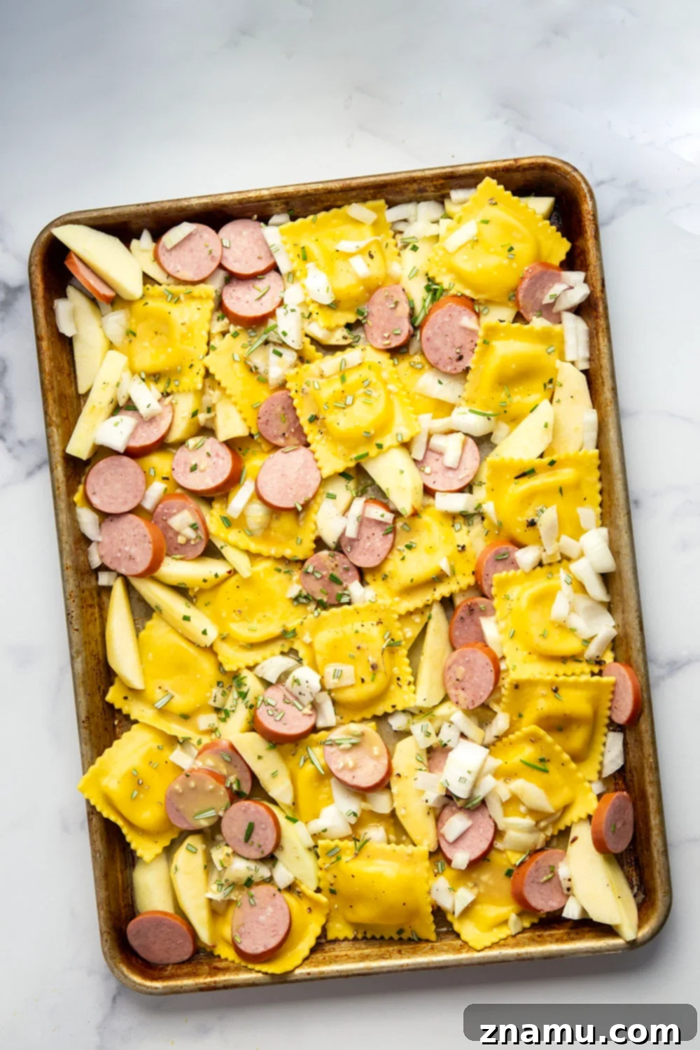 Sheet Pan Sausage, Apple, and Ravioli Bake 3 Close-up of roasted sheet pan ravioli with browned sausage, tender apple slices, and fresh kale, highlighting the rich maple mustard glaze.