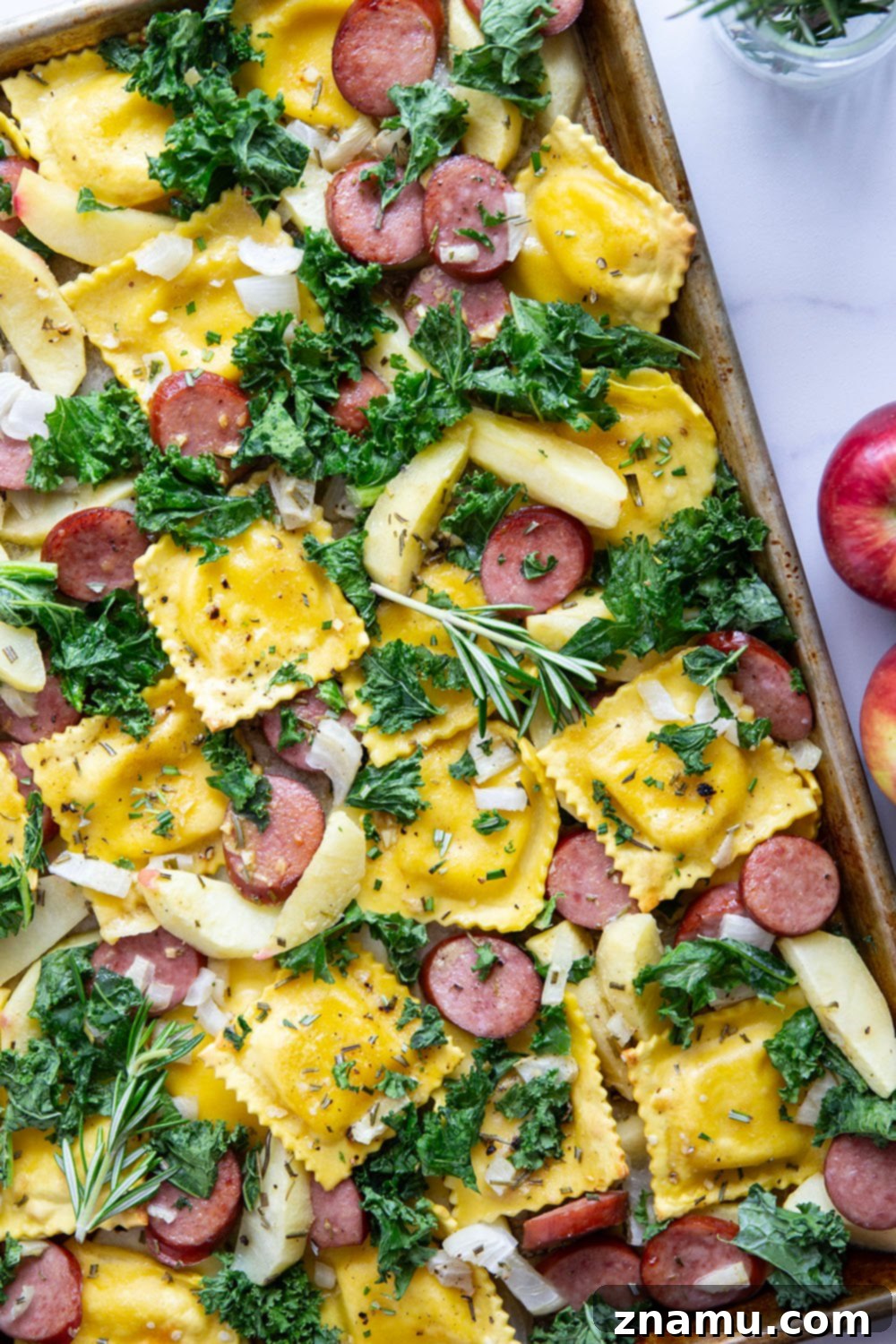 Sheet Pan Sausage, Apple, and Ravioli Bake 5 Close-up of savory sausage and sweet apple slices, uniformly cut, coated in the delicious maple mustard sauce before roasting.