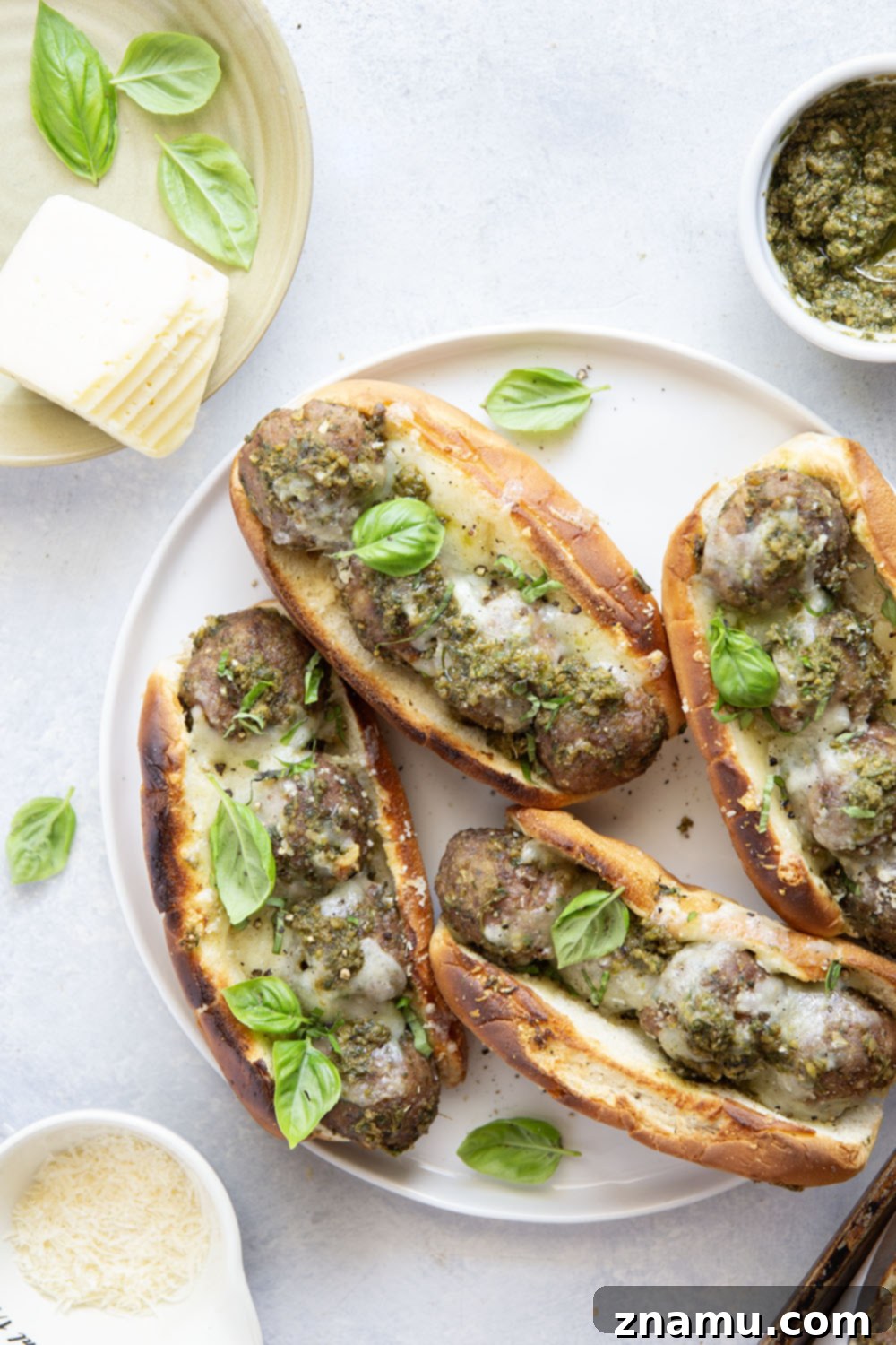 A perfectly broiled pesto meatball sandwich on a cutting board, ready to be enjoyed.