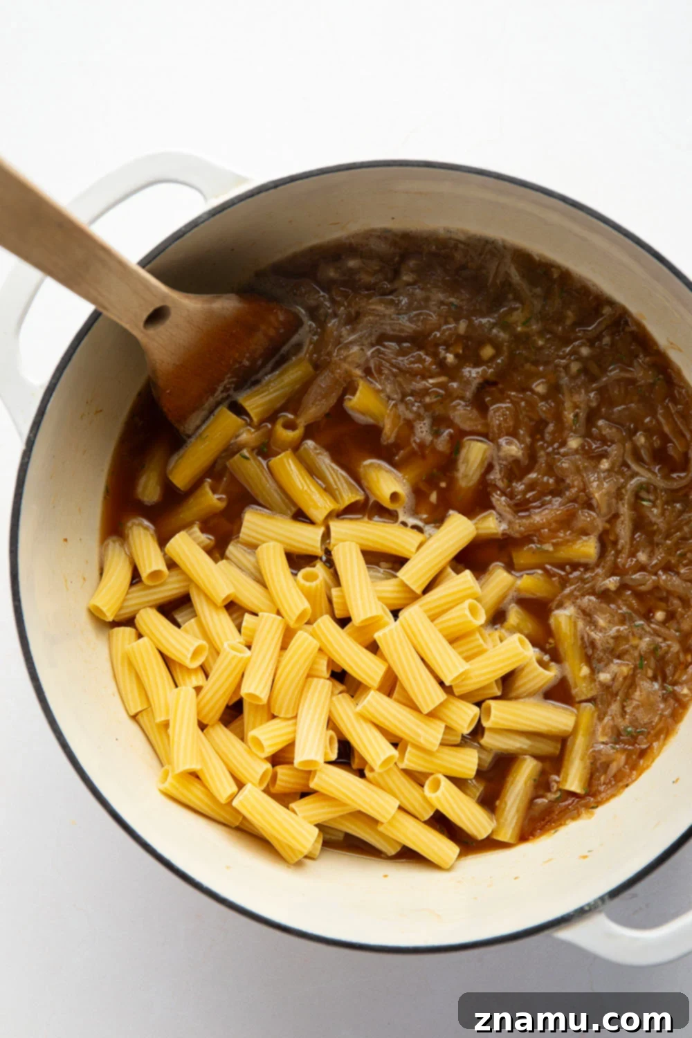 Cheesy One-Pot French Onion Pasta 4 A serving of French onion soup pasta in a bowl, showing off the melted Swiss and provolone cheese pull and savory sauce.