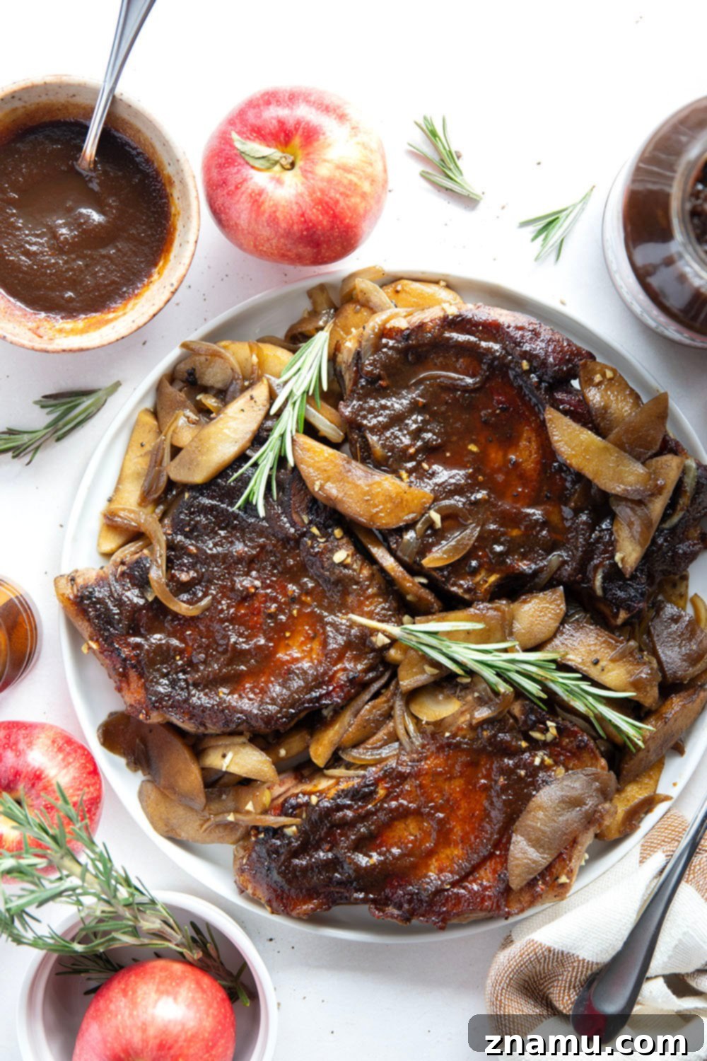Sticky Apple Butter Pork Chops 6 A serving of glazed apple butter pork chops on a rustic plate, with roasted apples and onions, and a side of mashed potatoes, ready to be enjoyed.