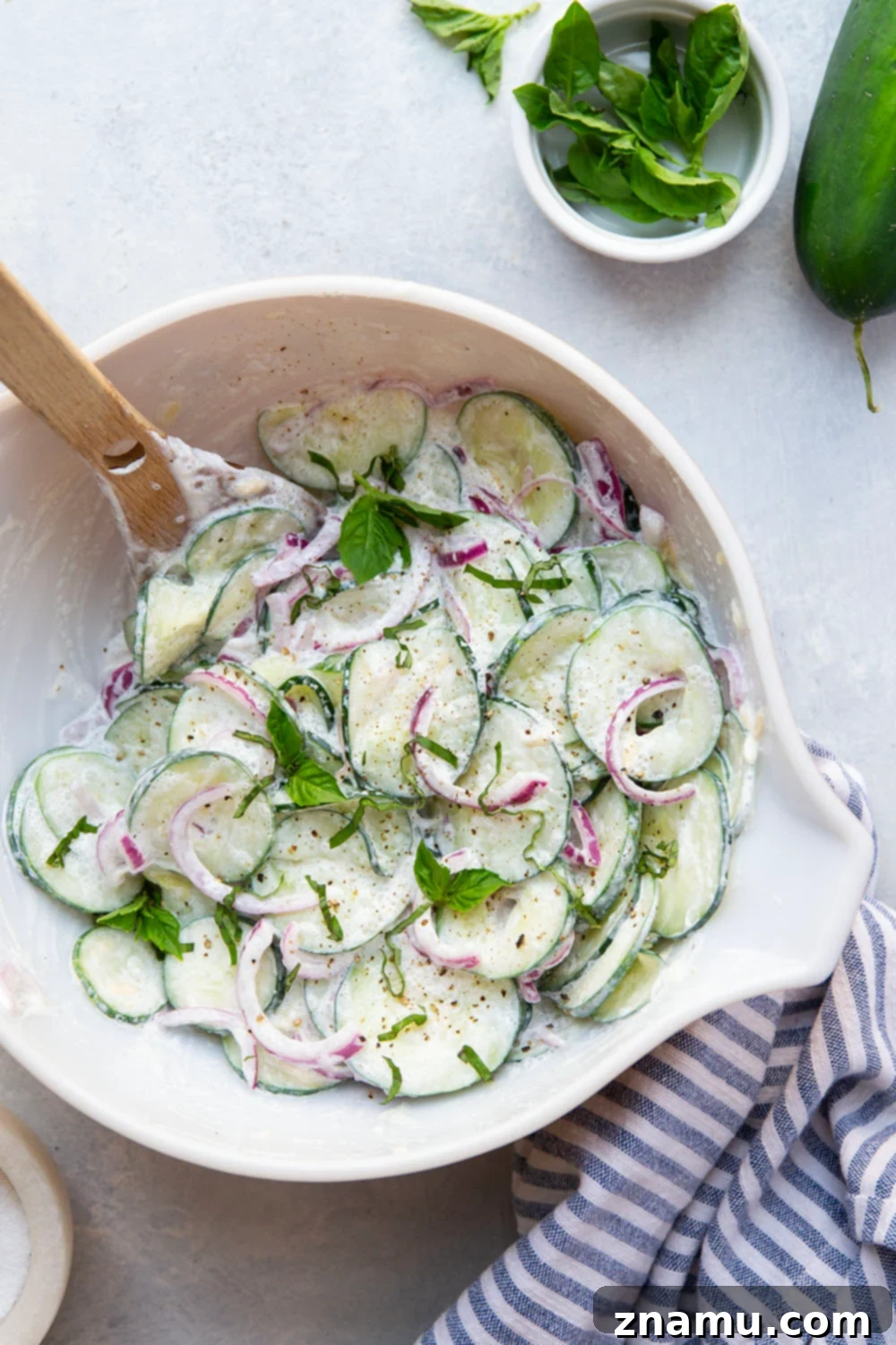 Velvety Basil Cucumber Delight 3 Close-up shot of the creamy basil cucumber salad, highlighting the tender red onion slices mixed with crisp cucumbers, coated in a luscious sour cream dressing.