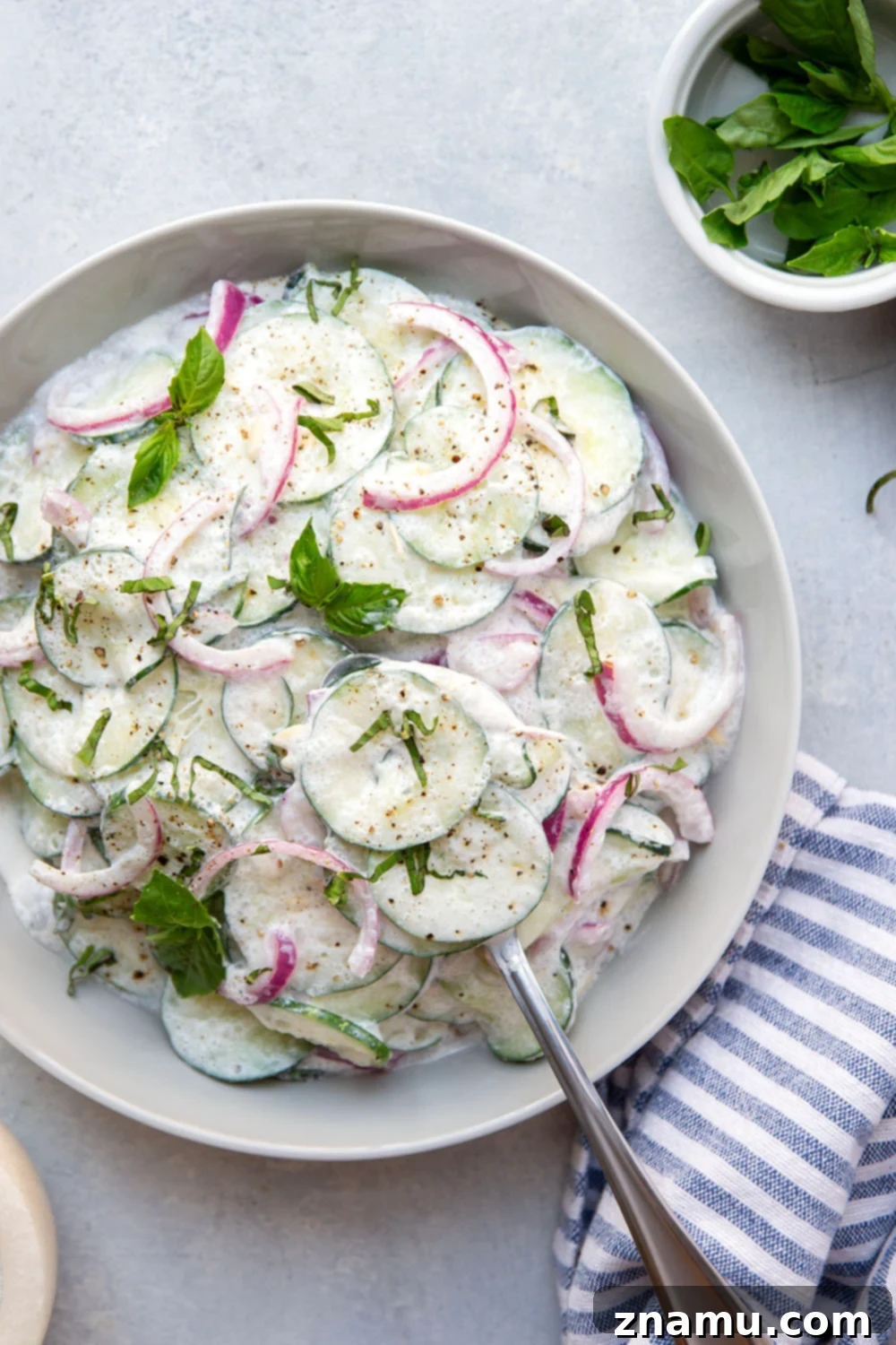 Velvety Basil Cucumber Delight 6 A generous serving of creamy basil cucumber salad in a rustic ceramic bowl, ready to be enjoyed as a refreshing side dish.