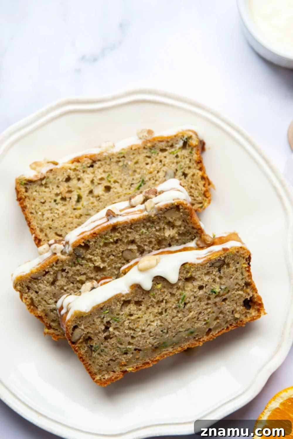 Several slices of glazed zucchini bread arranged artfully on a plate, ready to be served.