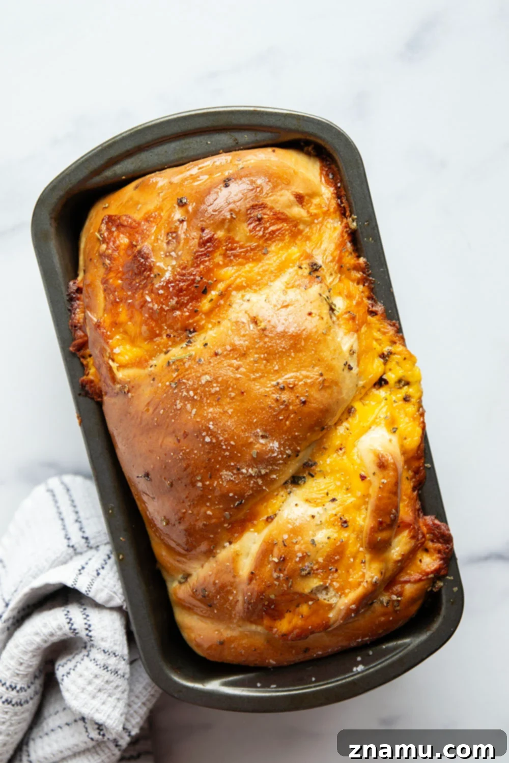 Irresistible Homemade Cheese Bread 3 Close-up of a thick slice of homemade cheese bread showing the intricate swirls of melted cheddar cheese and the fluffy texture.