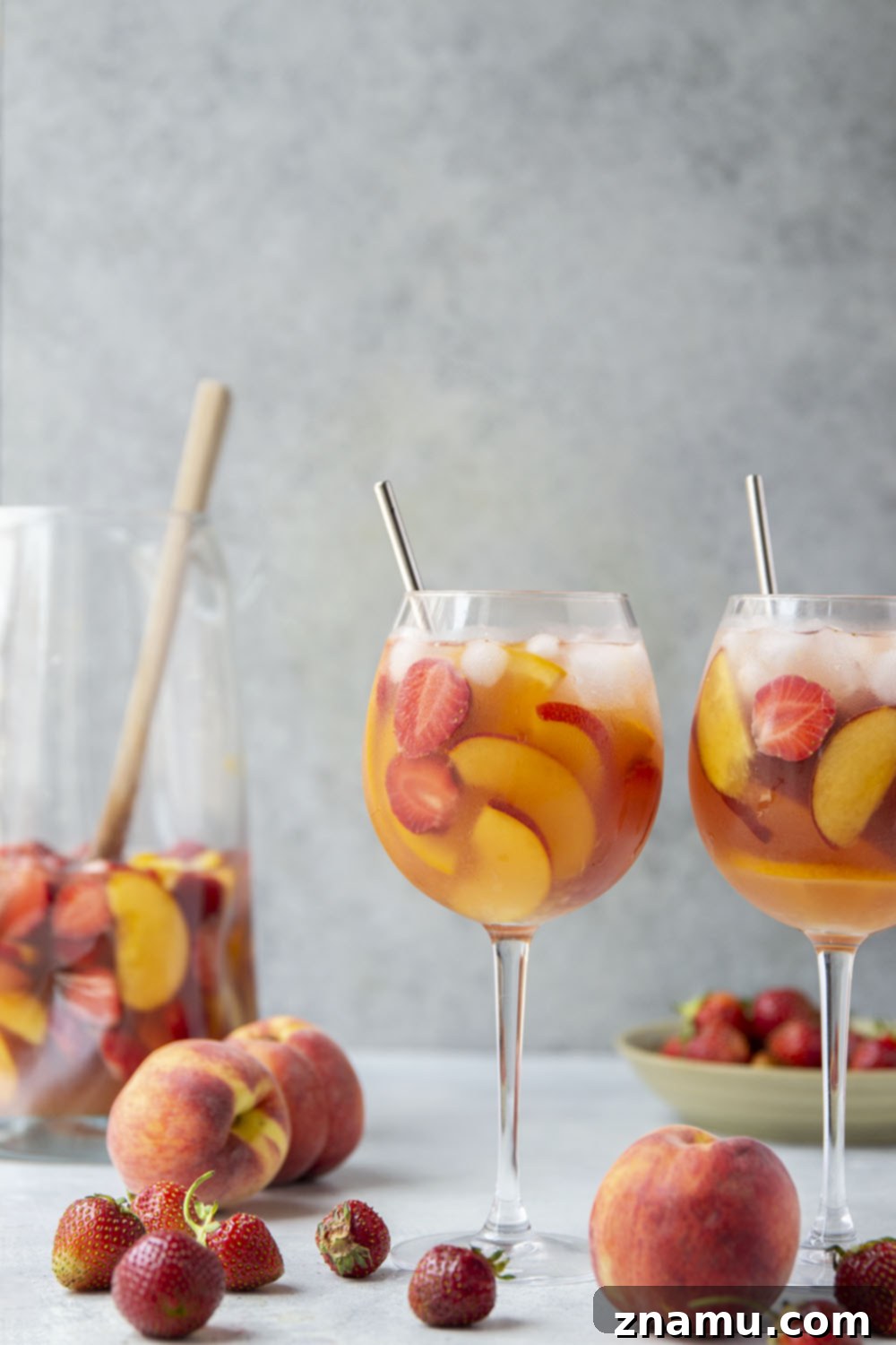 Sun-Kissed Peach Strawberry Sangria 2 A large pitcher of vibrant Strawberry Peach Sangria, brimming with fresh peach slices, ripe strawberries, and orange wedges, ready to be served over ice.