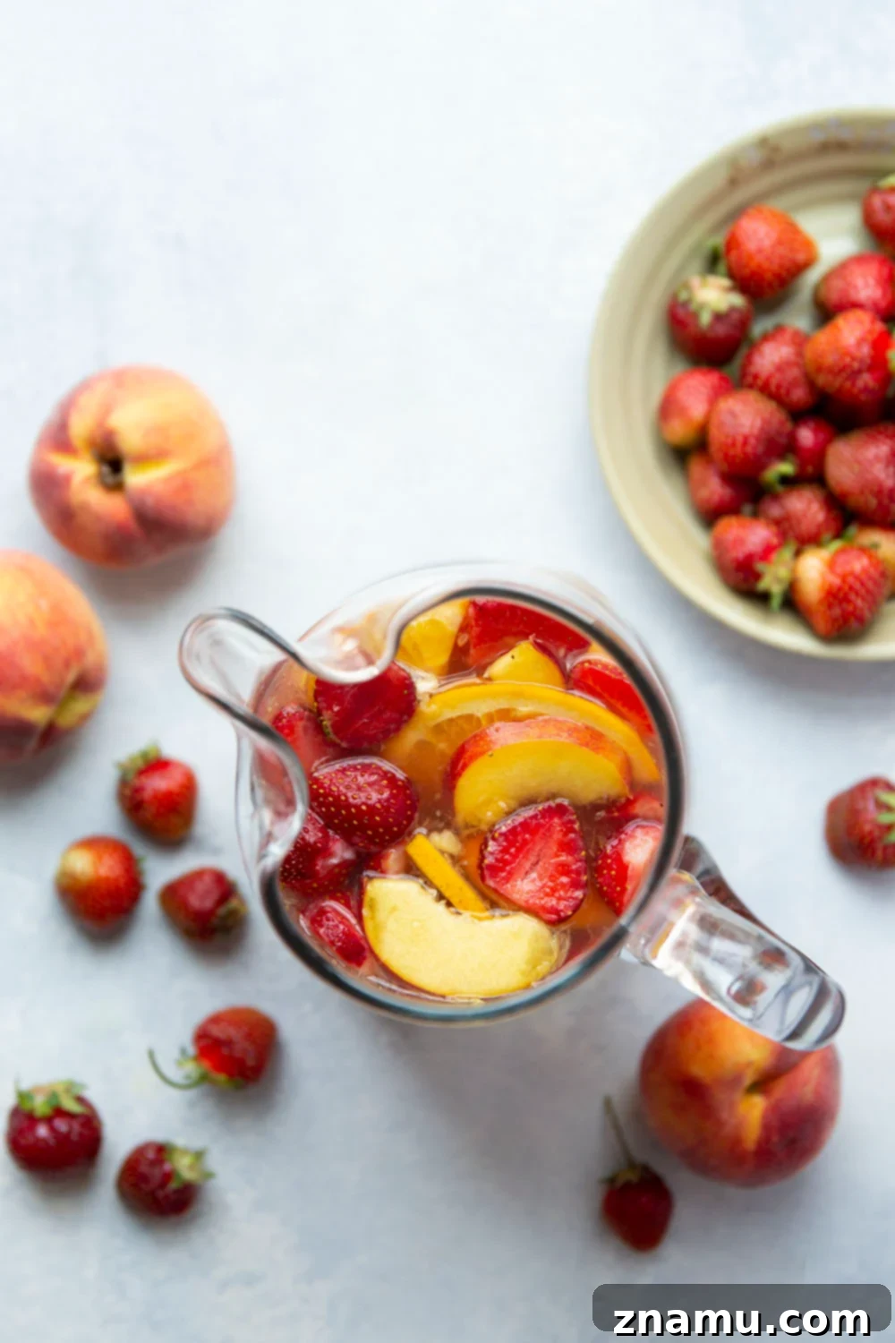 Sun-Kissed Peach Strawberry Sangria 3 A close-up of Strawberry Peach Sangria in a glass, showcasing the beautiful layers of fruit and the vibrant color of the drink, perfectly chilled with ice.