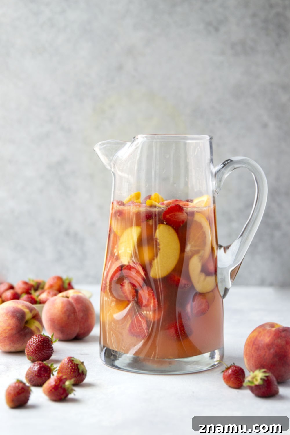 Sun-Kissed Peach Strawberry Sangria 5 A vibrant glass of Strawberry Peach Sangria on a wooden table, garnished with fresh mint, inviting for a refreshing sip.