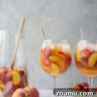 Strawberry Peach Sangria in a glass with fresh fruit slices, a refreshing summer drink recipe.