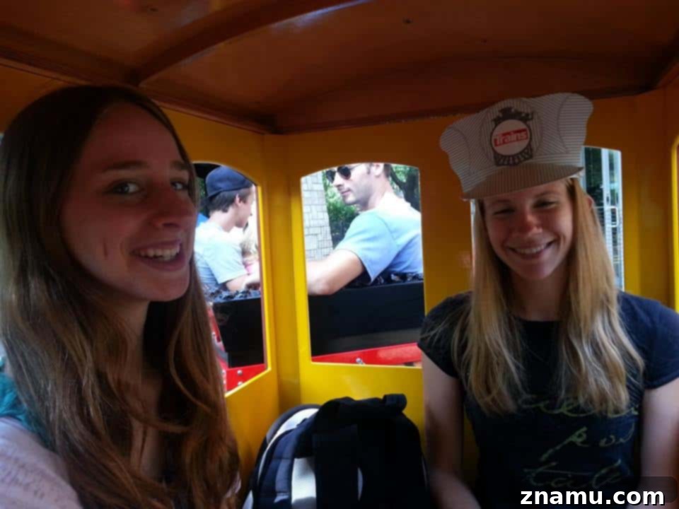 Reliving Summer 2014 22 Jessica and another person on a zoo train, both wearing playful hats and smiling broadly.