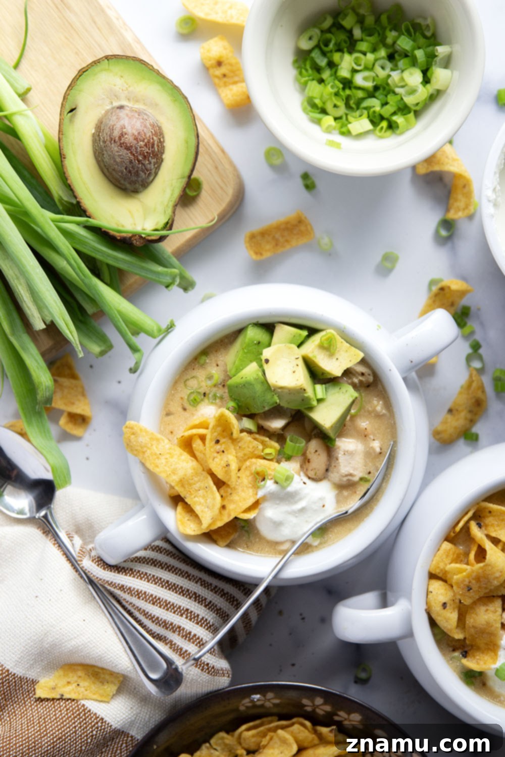 Ultimate White Chicken Chili 6 A large pot filled with creamy white chicken chili, garnished with fresh cilantro and lime wedges, ready to be served.
