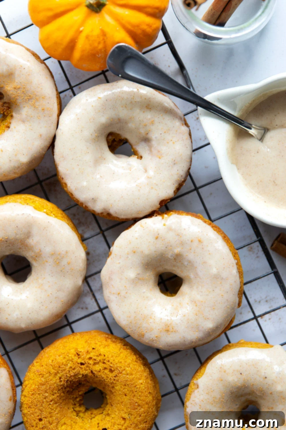 Super soft and fluffy baked pumpkin donuts are dipped in a rich cream cheese glaze and perfect for any fall occasion.