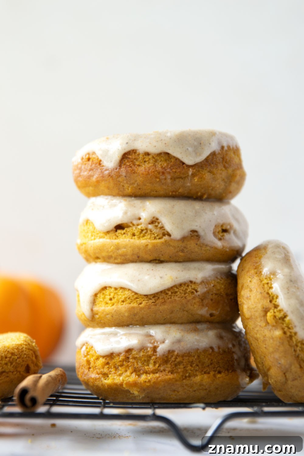 Super soft and fluffy baked pumpkin donuts are dipped in a rich cream cheese glaze and perfect for any fall occasion.