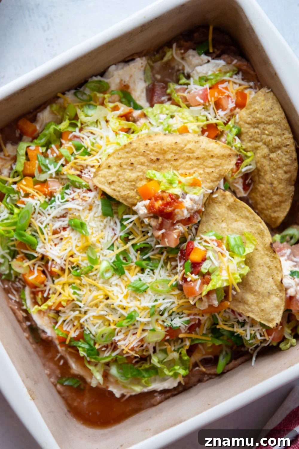 Ultimate Fiesta 7-Layer Dip 6 This 7-layer taco dip features layers upon layers of refried beans, a rich cream cheese filling, and lots of shredded lettuce, cheese, tomatoes, and peppers on top.