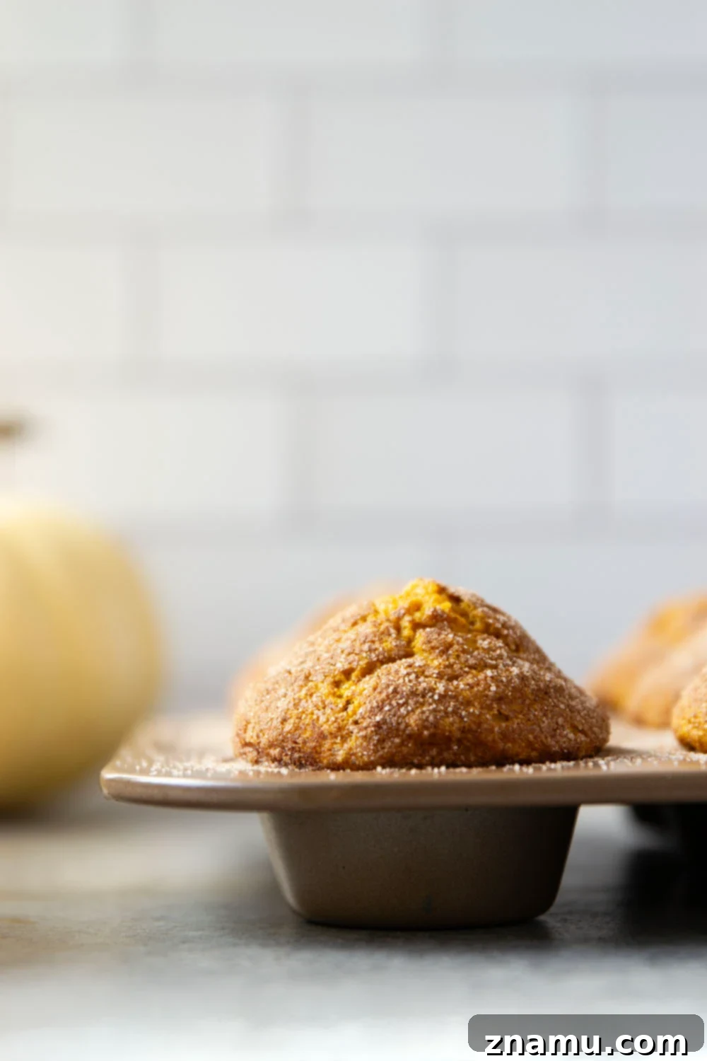 Tarçın Şekerli Balkabağı Muffin 4 Freshly baked pumpkin snickerdoodle muffins cooling on a wire rack, sprinkled with cinnamon sugar