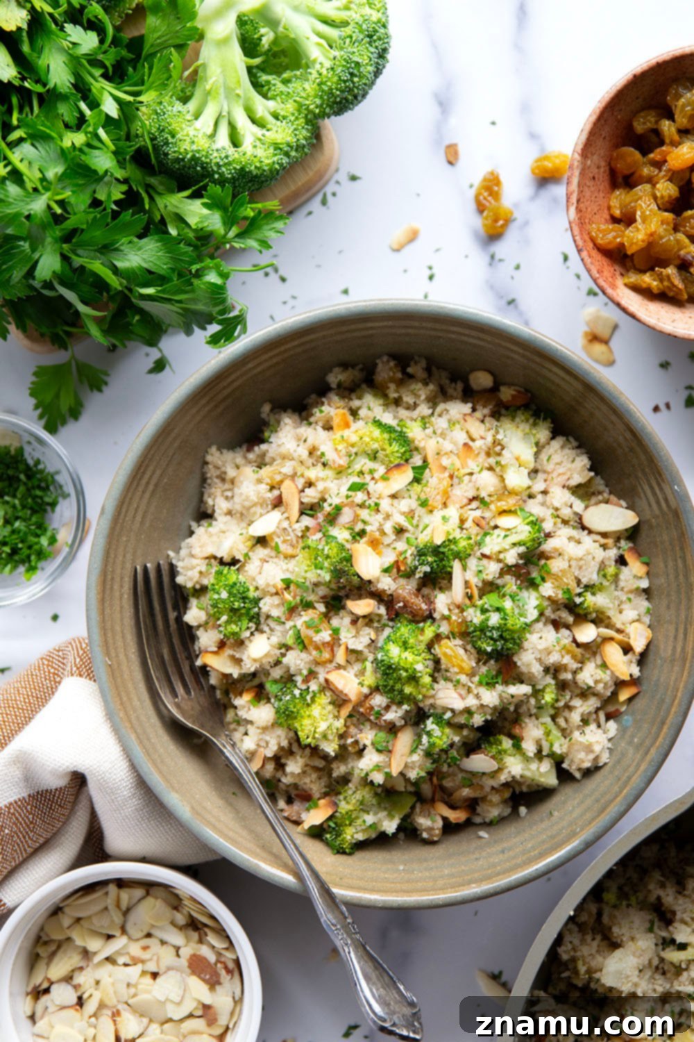 Flavorful Cauliflower Rice Pilaf 4 A bowl of fluffy Cauliflower Rice Pilaf, showcasing its rich texture, vibrant broccoli, and crunchy almonds, garnished with fresh herbs.
