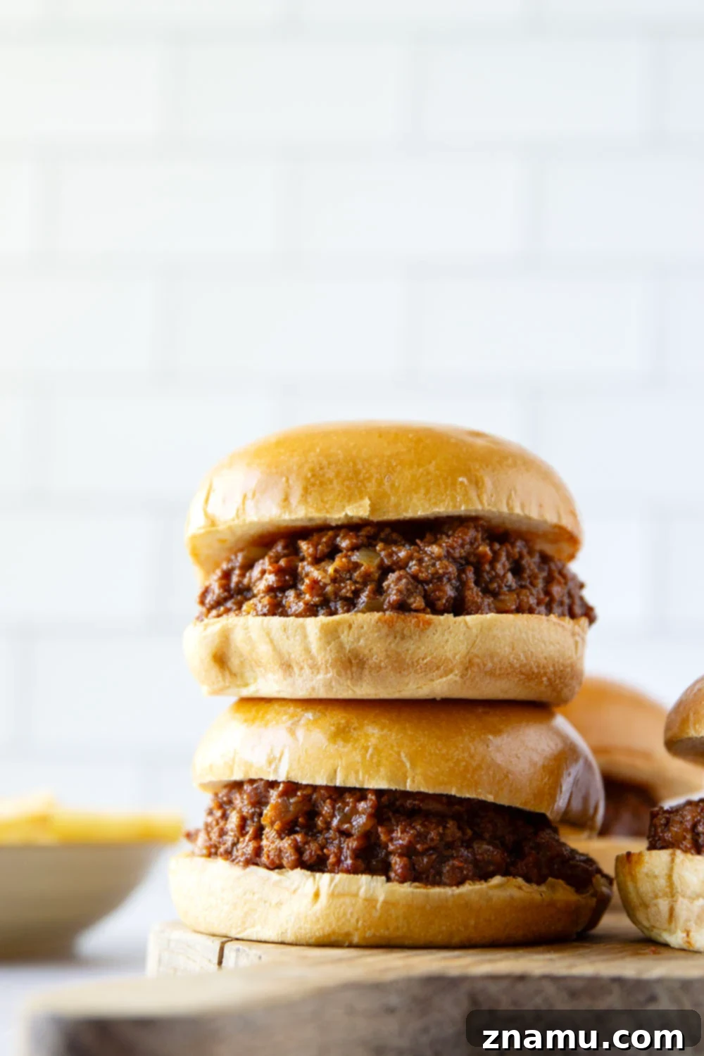 Effortless Slow Cooker Sloppy Joes 6 Slow cooker sloppy joes piled high on a bun with cheese and pickles.