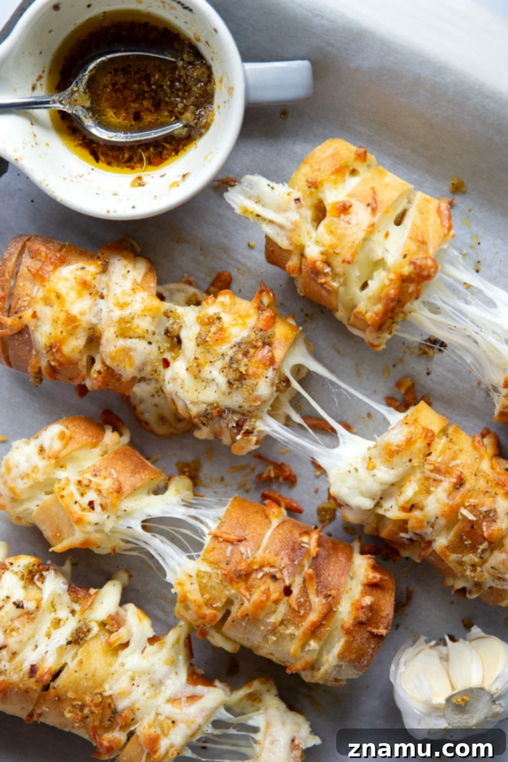 Cheesy Garlic Pull-Apart Bread 2 This cheesy garlic hasselback bread is baked with gooey mozzarella and Parmesan between slices and brushed in a garlicky herb butter.