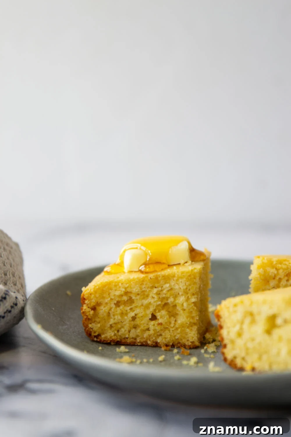 Golden Buttermilk Cornbread 2 A warm slice of honey buttermilk cornbread, golden brown with a tender crumb, perfect for chili.