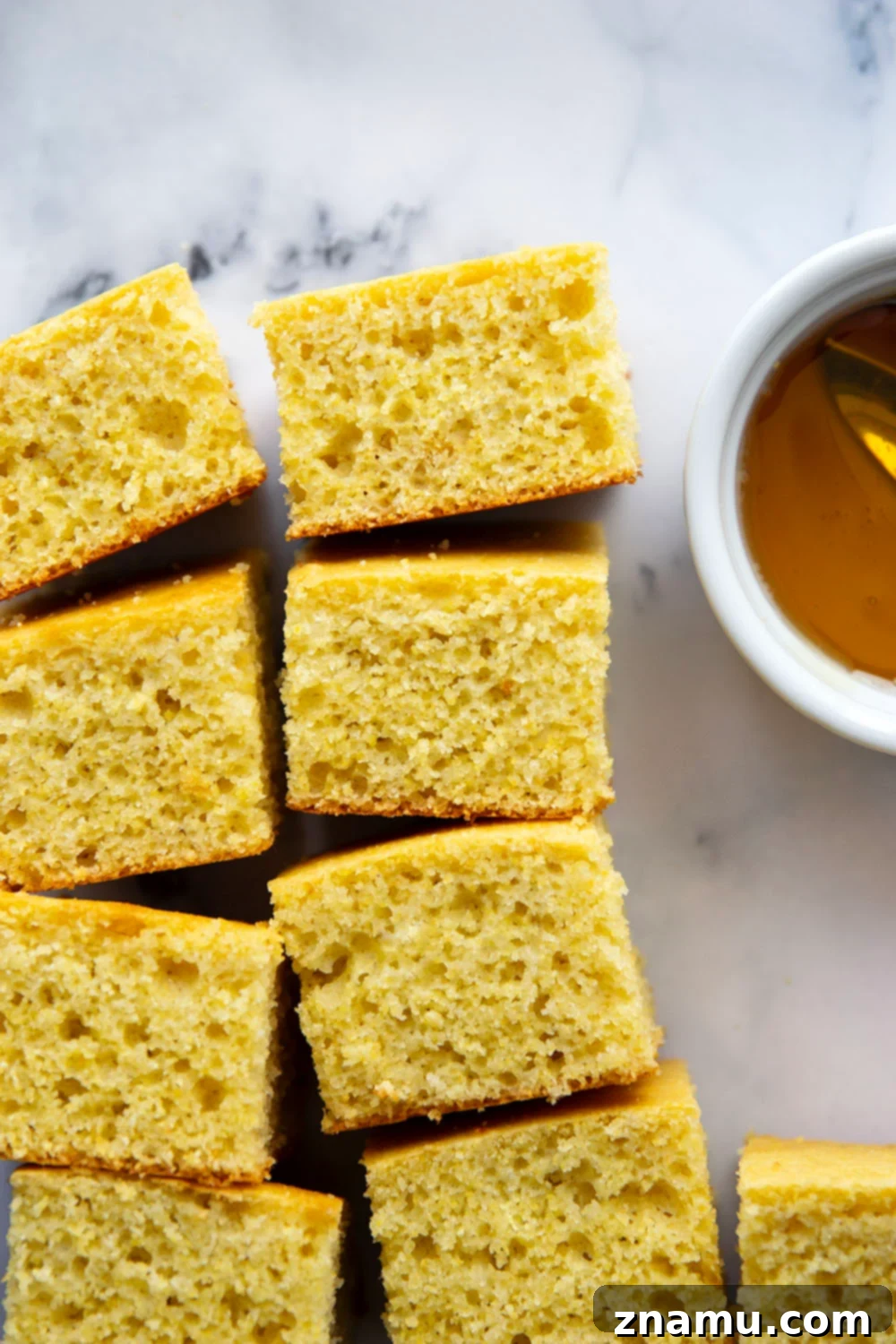 Golden Buttermilk Cornbread 5 A warm, golden square of buttermilk cornbread topped with melting butter and honey.