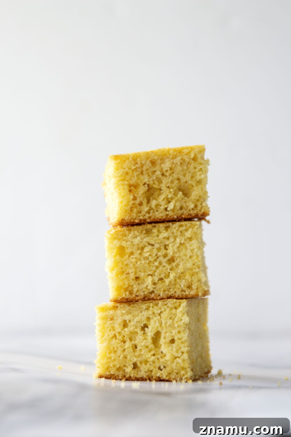 Golden Buttermilk Cornbread 6 A stack of golden buttermilk cornbread squares on a cooling rack, steam gently rising.