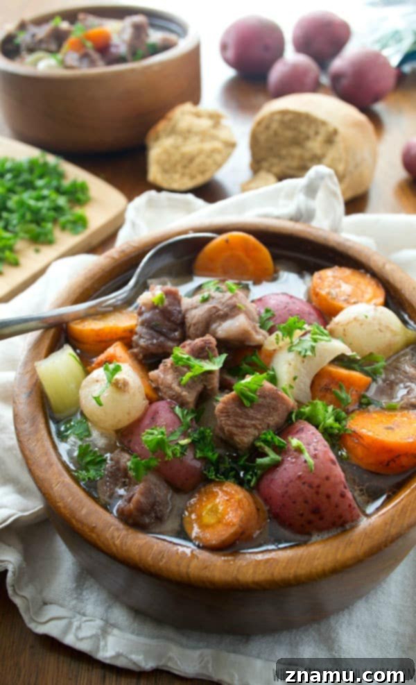 Comforting Slow-Cooker Harvest Beef Stew 3 Close-up of a bowl of slow cooker beef stew with crusty bread, showcasing rich broth and chunky vegetables.