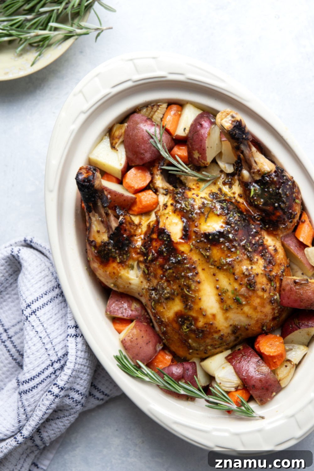 A perfectly golden honey mustard roast chicken, surrounded by roasted red potatoes and carrots, ready to be served.