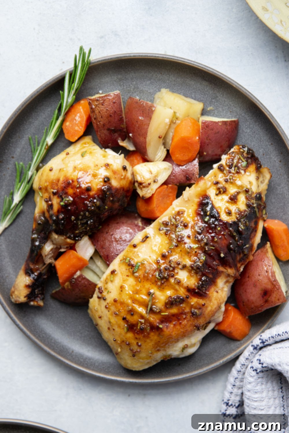 Platter of sliced honey mustard roast chicken breast and thigh meat, alongside roasted vegetables.