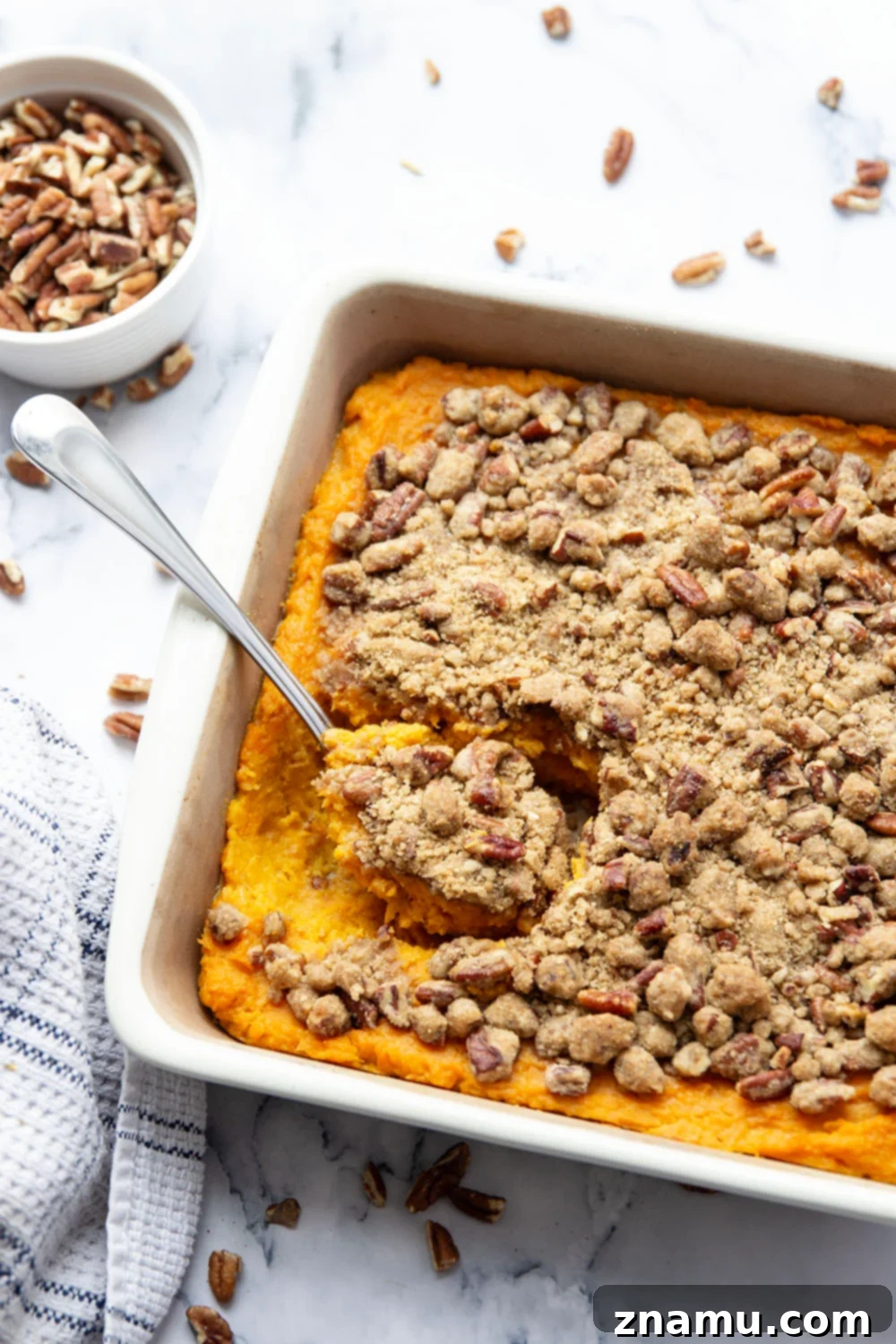 Velvety Sweet Potato Bake with Crunchy Pecan Topping 6 Close-up of a serving of sweet potato casserole, highlighting its creamy texture and the crunchy pecan streusel on top.